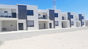 A modern building with multiple balconies, a covered entrance, and a clear sky. - Condo Casamar 3 by Kivoya (Puerto Peñasco)