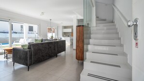Ein modernes Interieur mit einer Treppe, einer Couch und Blick durch eine Glastür.