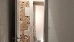 Een deur die leidt naar een kamer met een stenen muur.