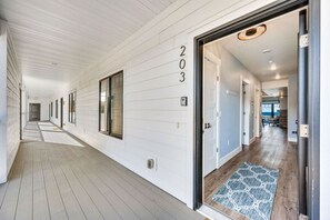 A corridor with a wooden floor, white walls, and a door marked '203'. - Marina Luxe Overlooking Sister Bay Marina (Sister Bay)