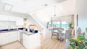Une cuisine moderne avec des meubles blancs, un plan de travail en granit et un coin repas comprenant une table ronde et des chaises.