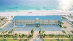 Un grand hôtel avec un toit bleu, une piscine et un parking.