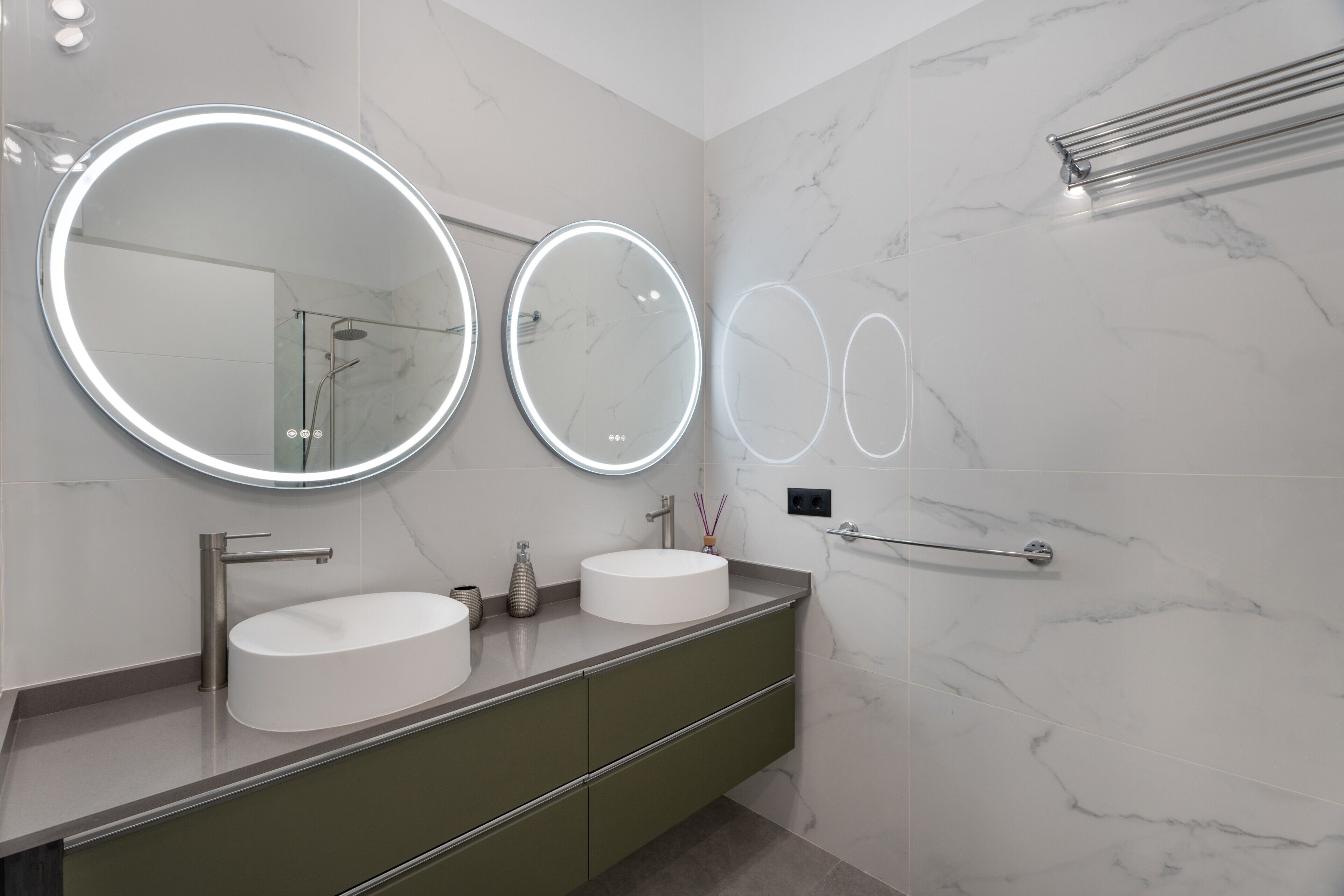 Une salle de bain avec deux miroirs ronds, un lavabo et un porte-serviettes.