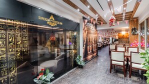 Un interior de hotel con una recepci ón, una pared con jeroglíficos y un comedor con mesas y sillas.