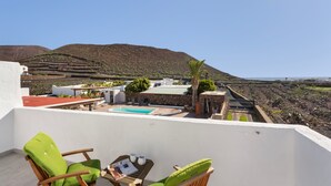 Een terras met een zwembad, stoelen en een tafel.