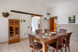 A dining area with a wooden table and chairs, a cabinet with glass doors, and a tiled floor.