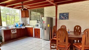 Una cocina con armarios de madera, un refrigerador, un microondas y una mesa de comedor con sillas.