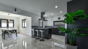 Una cocina moderna con comedor, que incluye una isla grande, taburetes de bar y una planta en maceta.