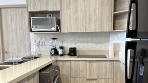 A modern kitchen with wooden cabinets, a built-in microwave, a washing machine, and a refrigerator. - Departamento 5ta Av-Playa & Rooftop Pool (Playa del Carmen)