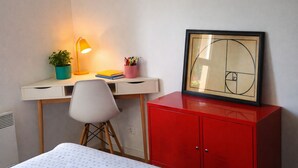Una habitación pequeña con escritorio, silla y un armario rojo.