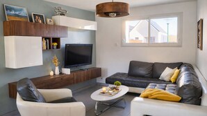 Una sala de estar moderna con televisor de pantalla plana, sofás de cuero, una mesa de centro e iluminación colgante.