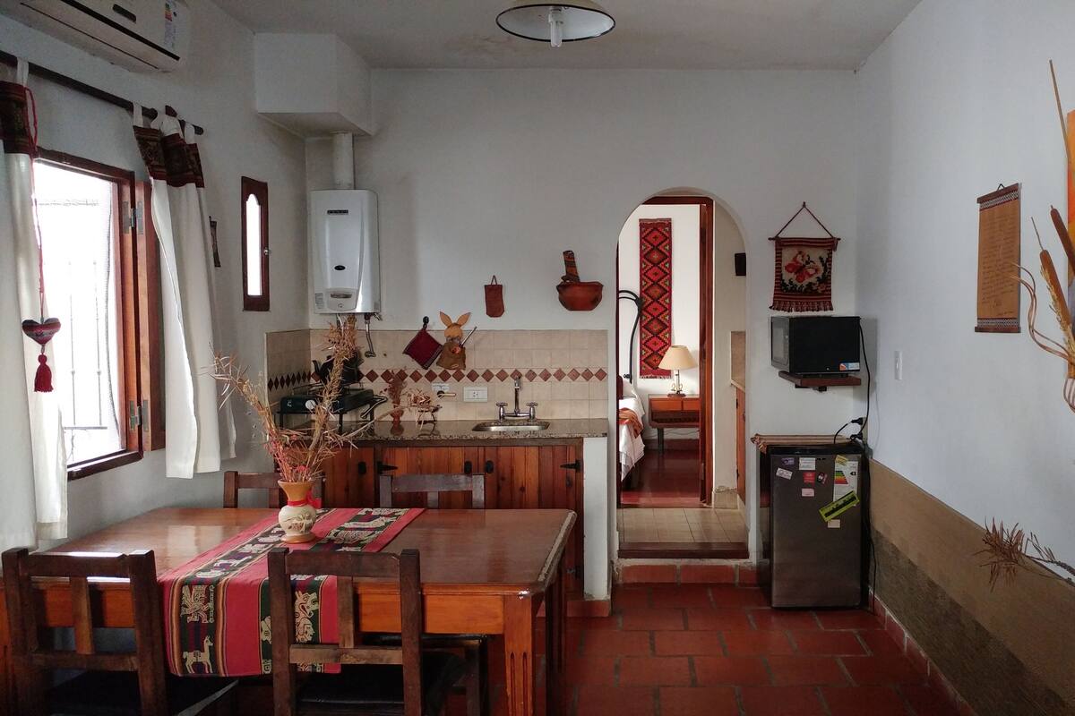 A compact kitchen with a dining area, a refrigerator, and a television.