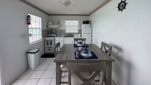 A compact kitchen with a dining table, white cabinets, a stove, and a refrigerator. - Seashore Sleeps Book Your Winter Getaway Now! (Black Point)