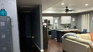 Una cocina moderna con suelo de madera oscura, un sofá beige y un ventilador de techo.