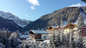 Une station de montagne avec des bâtiments en bois, des arbres couverts de neige et un ciel dégagé.