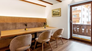Un comedor con una mesa de madera, sillas acolchadas, una planta en maceta y un cuadro en la pared.
