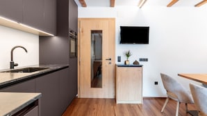 Una cocina moderna con puerta de madera, horno empotrado y televisor de pantalla plana montado en la pared.