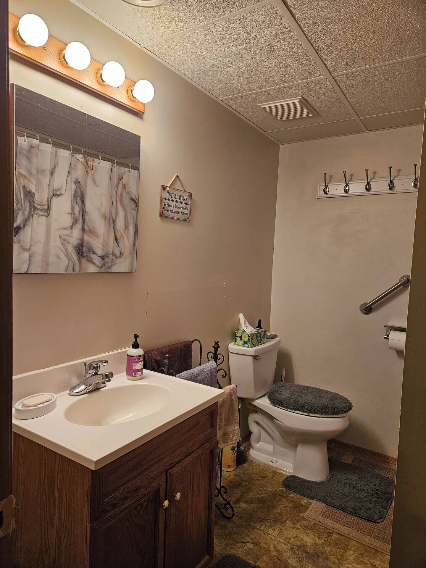 A bathroom with a vanity, sink, mirror, and a toilet.