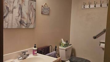 A bathroom with a vanity, sink, mirror, and a toilet.