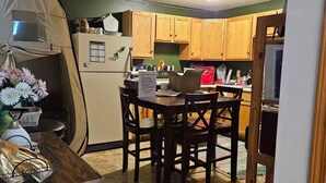 A compact kitchen with wooden cabinets, a refrigerator, and a dining table with chairs.