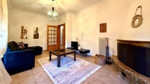 A living room with a sofa, a coffee table, a fireplace, and artwork on the walls. - Vasilikis Stone House (Kalabaka)
