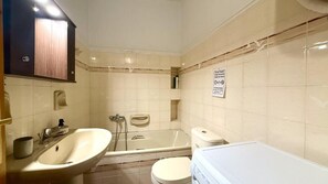 A bathroom with a bathtub, toilet, sink, and hand dryer. - Vasilikis Stone House (Kalabaka)