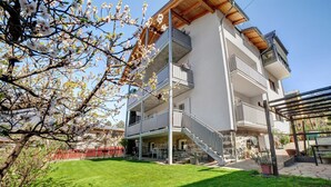 Un immeuble à plusieurs étages doté de balcons, d’un escalier et d’une pelouse bien entretenue.