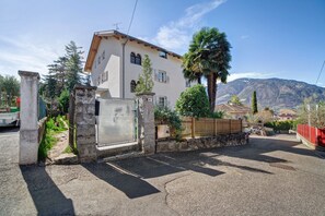 Un edificio residencial con una puerta de piedra, una valla de madera y una montaña al fondo.