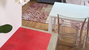 A living room with a grey sofa, a white table, and a red rug.