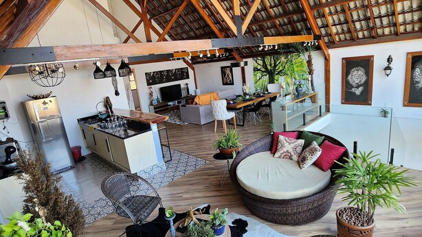 A spacious living area with a high ceiling, wooden beams, a central seating area with cushions, and various plants. - Private Room. SP Expo, Itaú, IBC, Congonhas, Zoo (São Paulo)