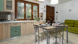 Una cocina moderna con armarios de madera, una mesa de comedor con sillas y un sofá verde en la sala de estar.
