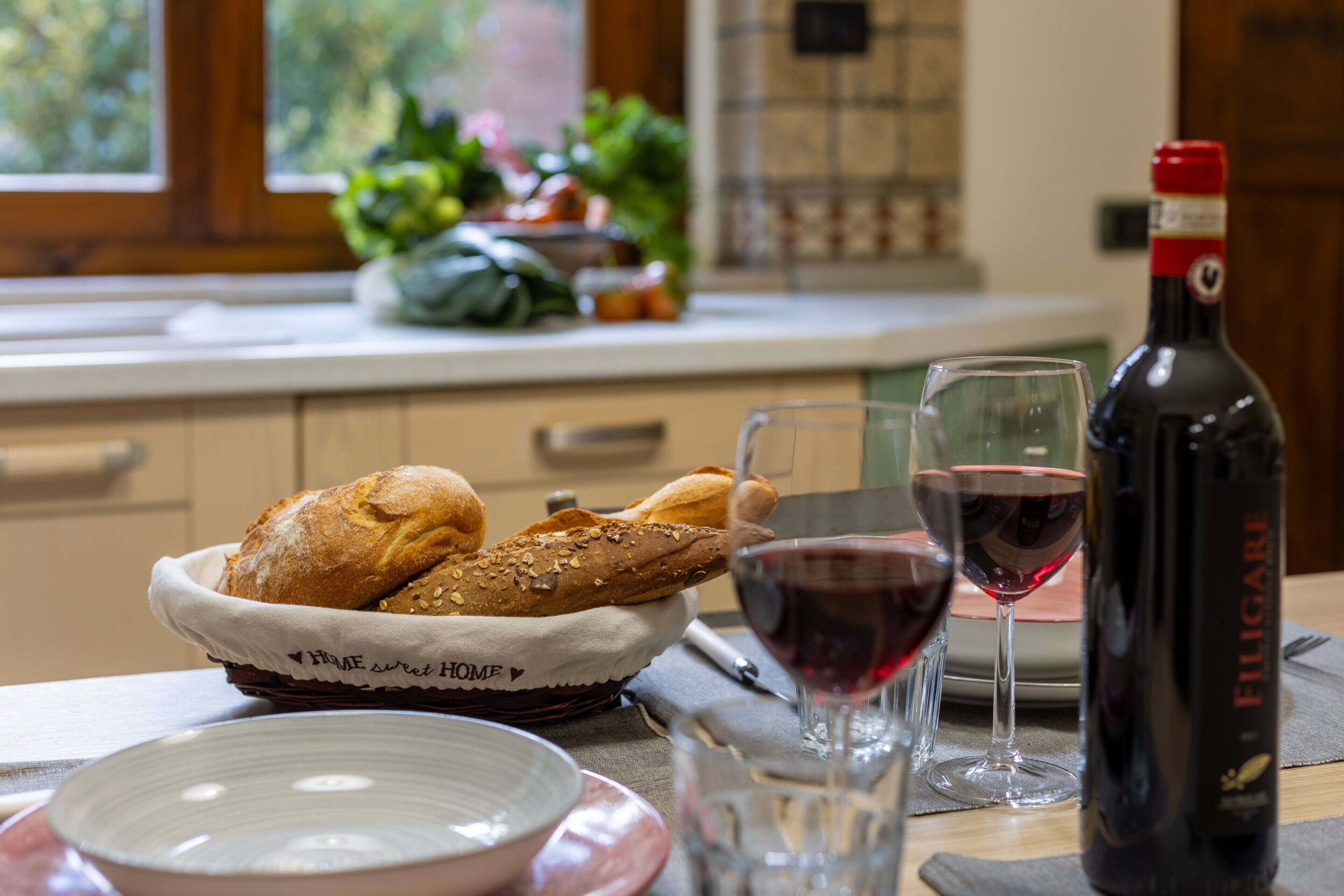 A kitchen with a bread basket, wine glasses, and a bottle of wine.