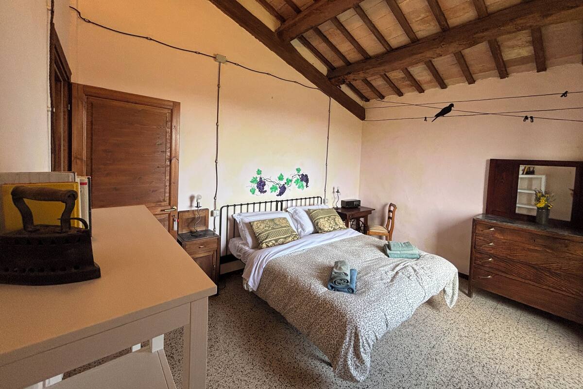 A bedroom with a bed, wooden furniture, a dresser, and a wall with a grapevine mural.
