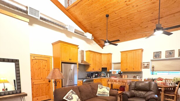 A spacious living room with a brown leather sofa, a coffee table, and a dining area with wooden furniture. - Peaceful Texas Retreat w/Gourmet Kitchen, Ranch Views, Optional MasterChef Meals (Lipan)