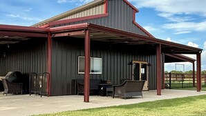 A large building with a covered patio area and outdoor seating. - Peaceful Texas Retreat w/Gourmet Kitchen, Ranch Views, Optional MasterChef Meals (Lipan)