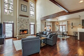 A spacious living room with a fireplace, large windows, and a high ceiling. - Mountain Modern Lodge, Ski/Golf, Hot Tub, Pool Table, Foosball, Poker Table (Breckenridge)