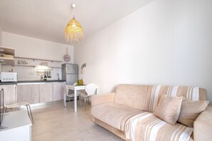Una sala moderna con un sofá, una mesa de comedor y una zona de cocina.