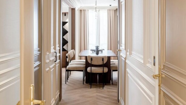 A hallway with a dining area at the end, featuring a chandelier and a table with chairs. - Merveil - Signature Suite - Opera - Bateliere (Paris)