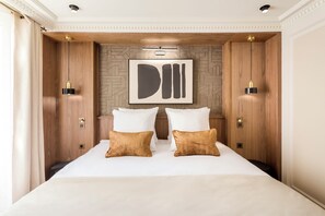 A hotel room with a large bed, two wooden wardrobes, a modern abstract painting, and a stone-patterned wall.