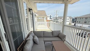 Un balcon abrité comprenant un canapé modulable, un fauteuil en osier et une petite table.