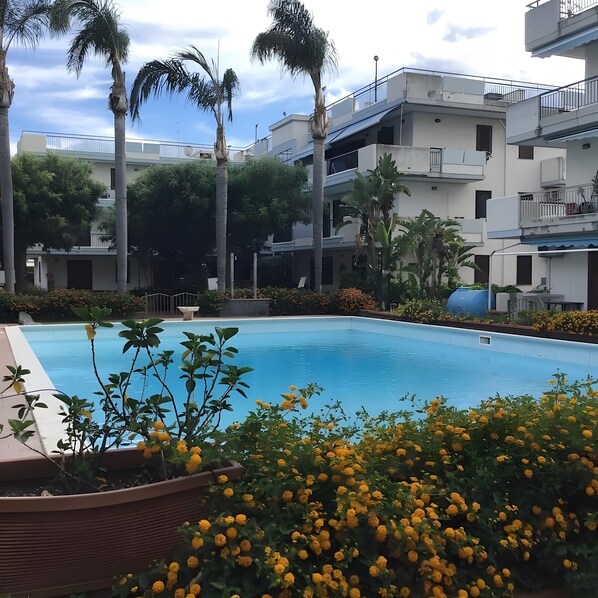 A swimming pool surrounded by greenery and buildings.