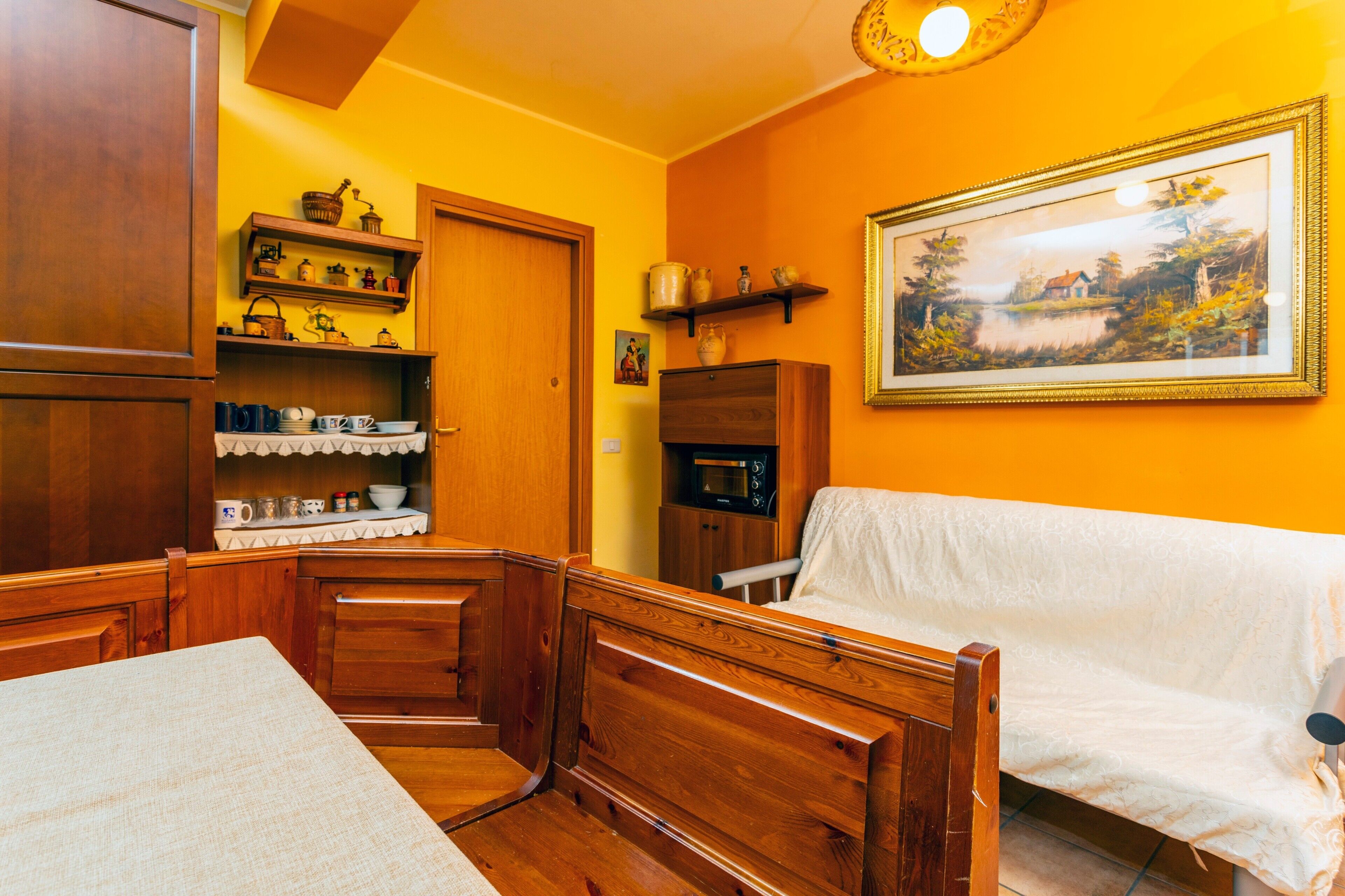 Una habitación acogedora con muebles de madera, un sofá blanco, una mesa de comedor y estantes con utensilios de cocina.