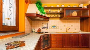 Een keuken met houten kastjes, een gasfornuis en een betegelde spatwand.