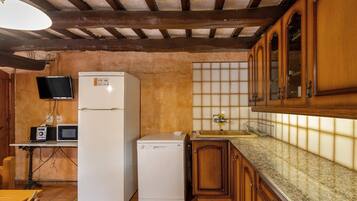 Una cocina con armarios de madera, microondas, refrigerador y salpicadero de azulejos.