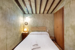 Une chambre à coucher avec une tête de lit en bois, un lit avec une literie blanche, une table de chevet avec une lampe et une armoire en bois.
