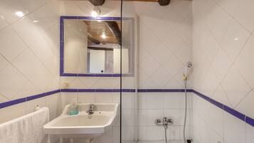 A bathroom with a white sink, mirror, and shower.