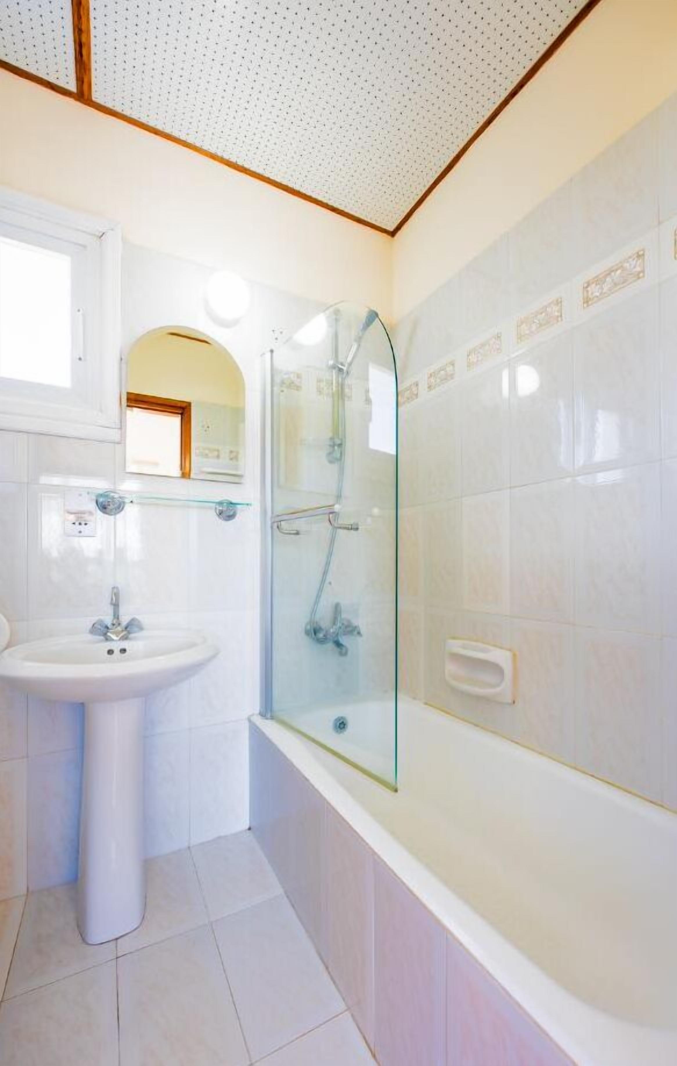 A bathroom with a pedestal sink, a glass shower enclosure, and a bathtub.
