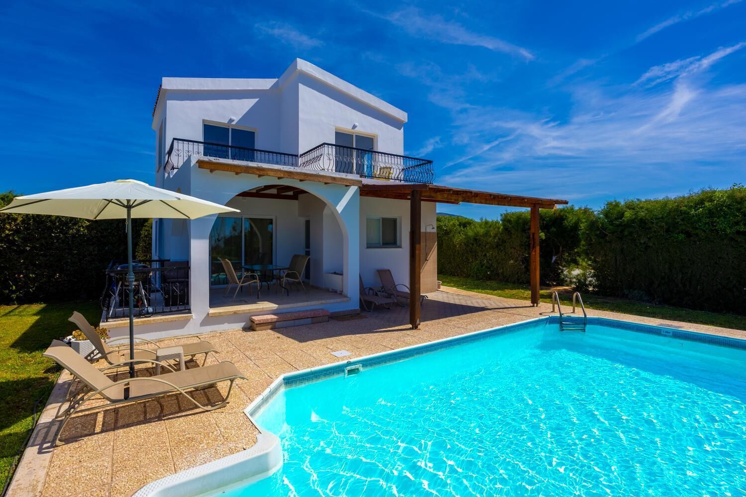 A modern two-story house with a swimming pool, outdoor seating, and a covered patio area.