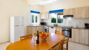 A modern kitchen with a dining area, featuring a refrigerator, microwave, oven, and washing machine.
