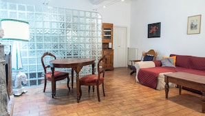 Ein Zimmer mit Esstisch und Stühlen aus Holz, einem roten Sofa und einem Holzschrank.